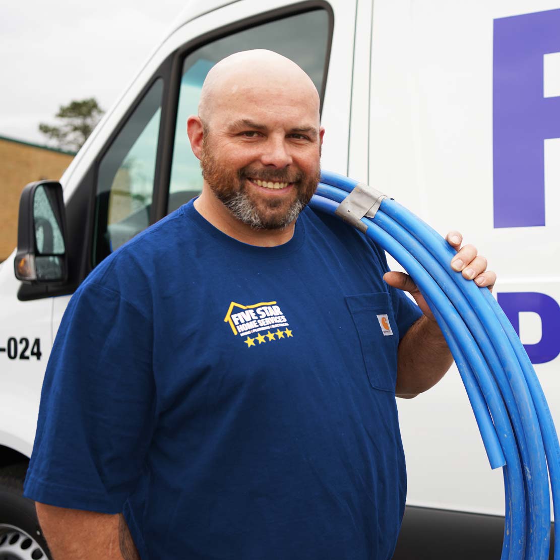 Plumber Holding Piping in Front of a Van