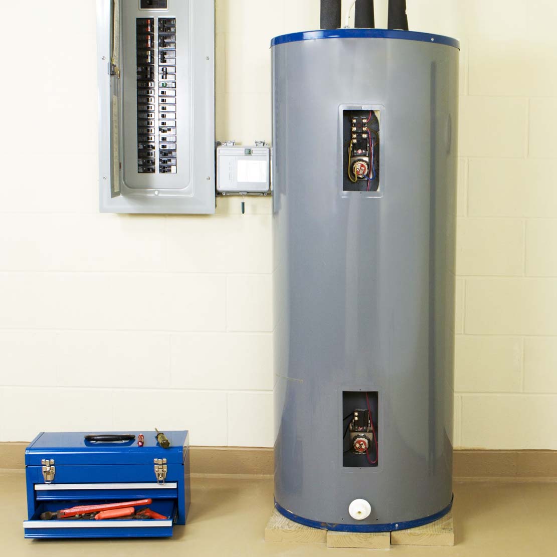 Electric water heater in a basement next to a toolbox