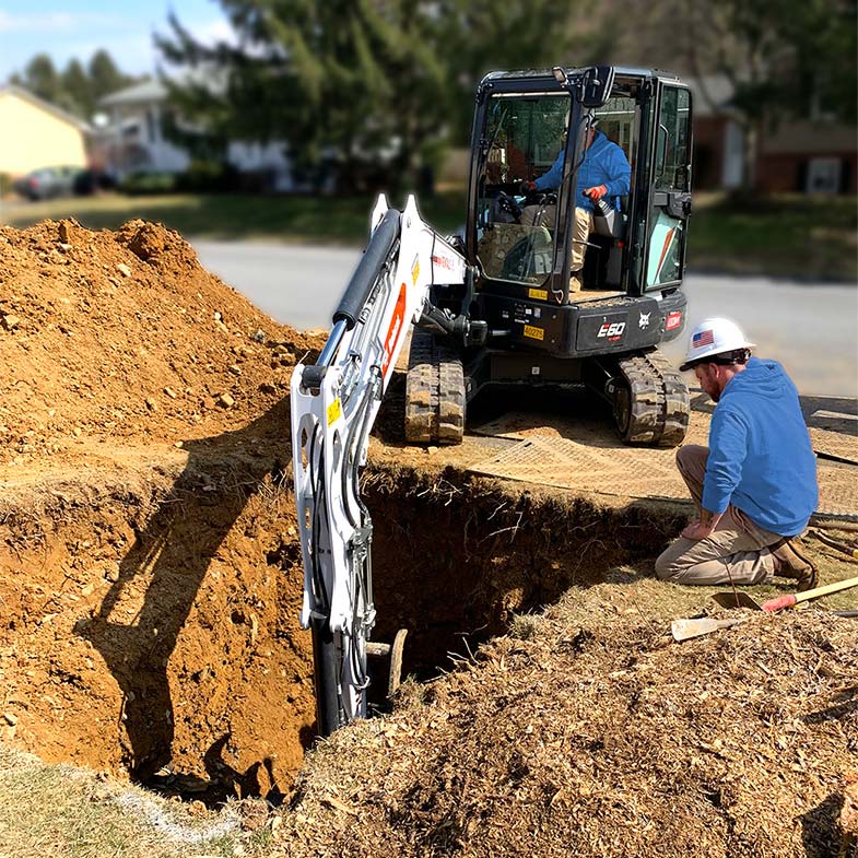 Two Plumbers digging a hole with an Excavator